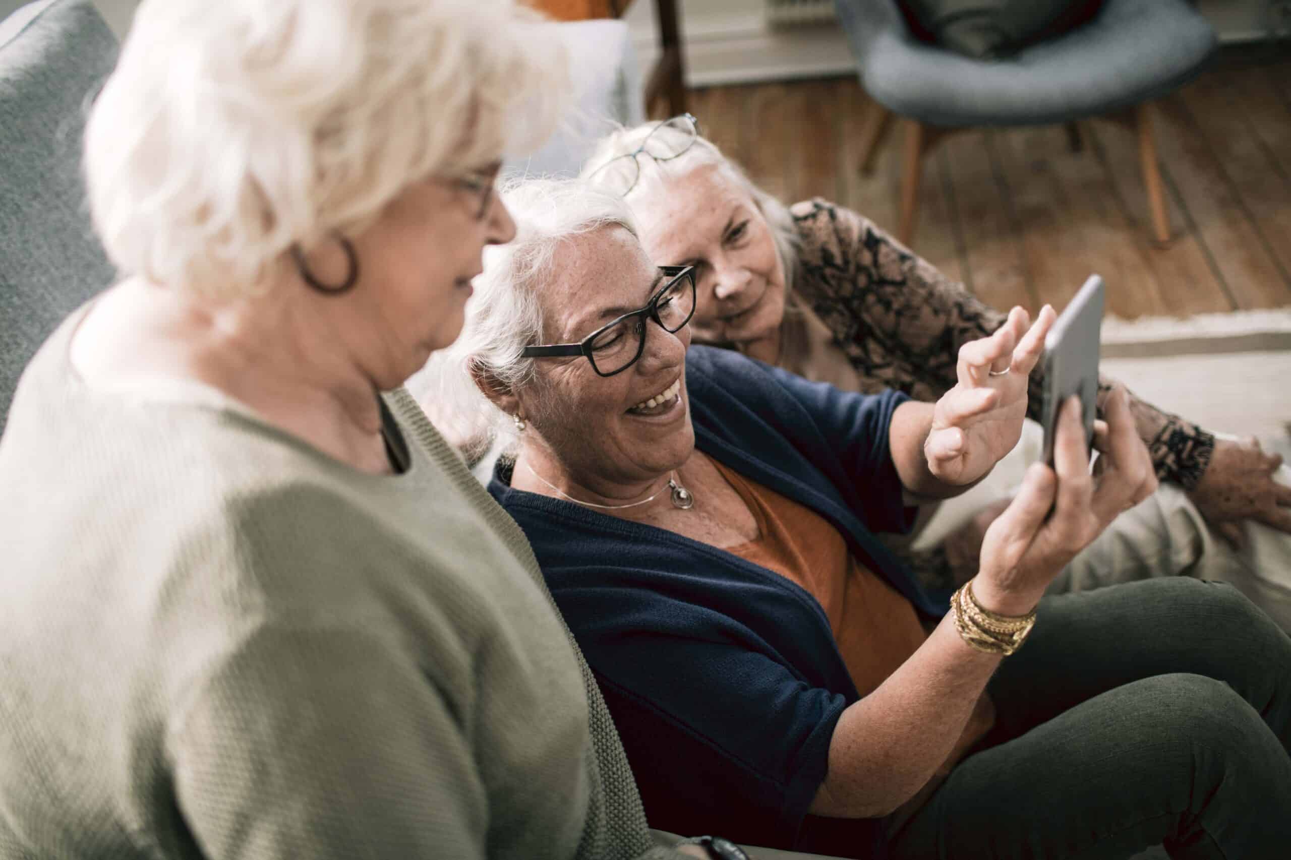 Close up of a group of senior women using a phone in their living room