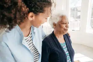 Care worker and elderly woman walk side by side